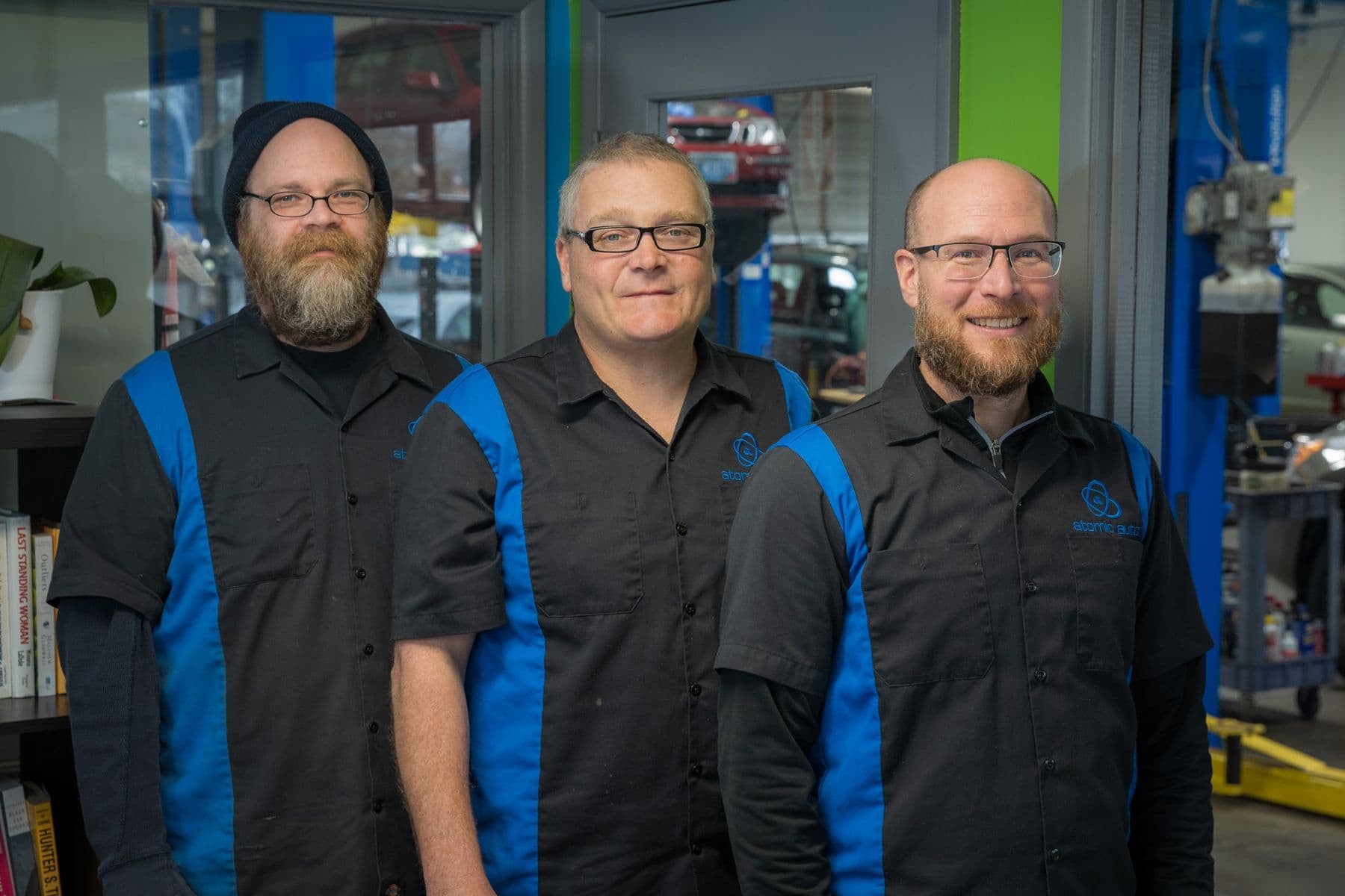 Travis Decker, owner, in the middle, with two of the Atomic Auto crew in the shop's blue and black work shirts