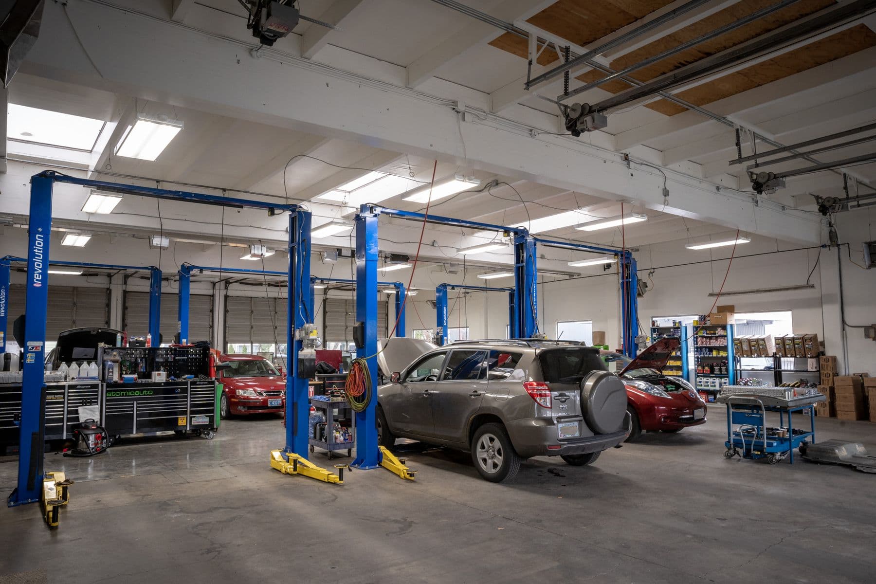 Atomic Auto's shop floor under the skylights, a RAV4, a Leaf and other cars up on the blue lifts