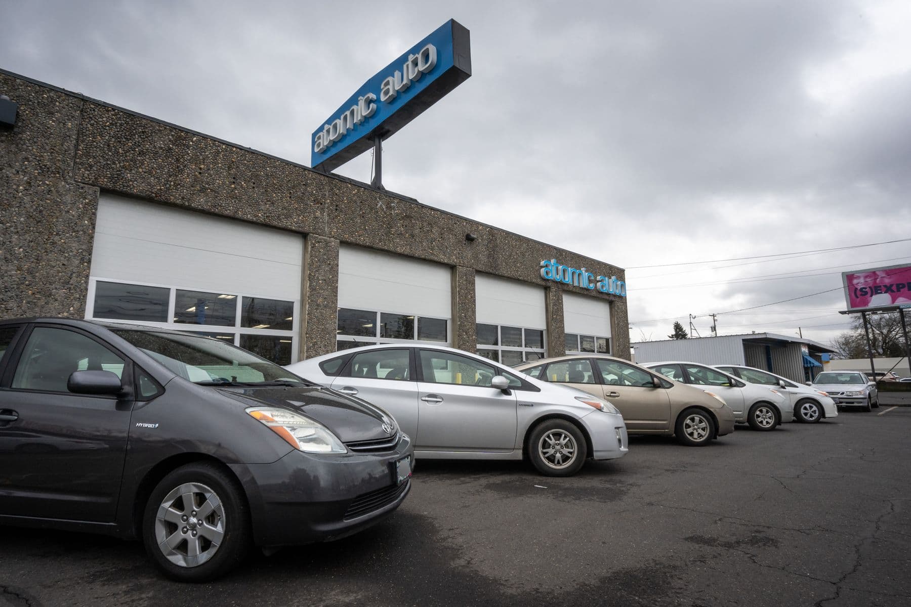 A row of Priuses of different generations parked along Atomic Auto's bays