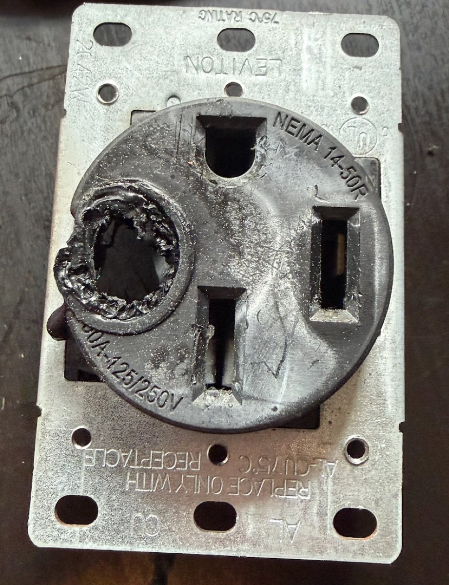 Front of a burnt residential Leviton NEMA 14-50R outlet with one hot contact melted out