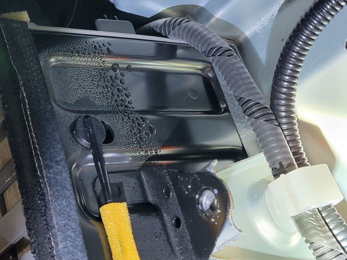 Beads of water and condensation on the painted body panel near the hybrid battery area, evidence of an ongoing water leak
