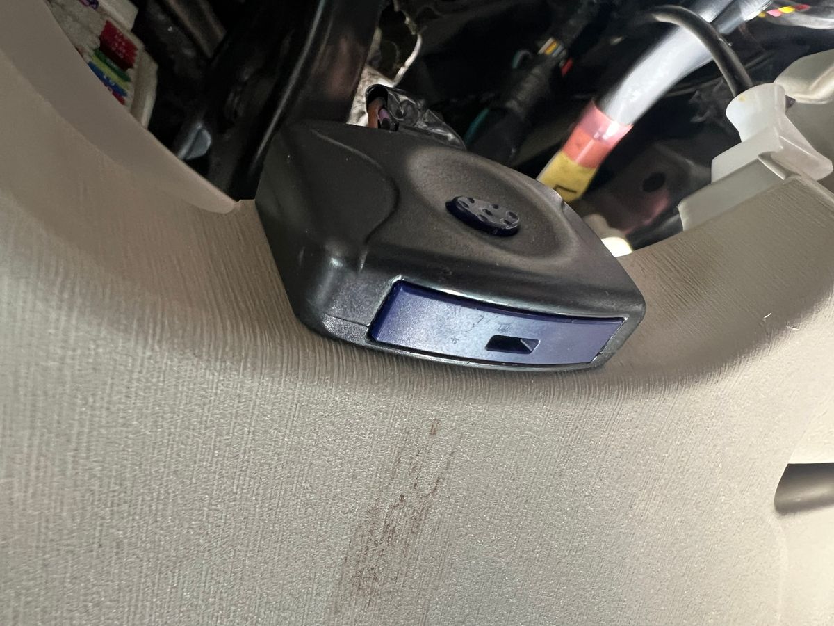 The aftermarket security module removed from a 2011 Toyota Prius, a black box with a blue LED indicator