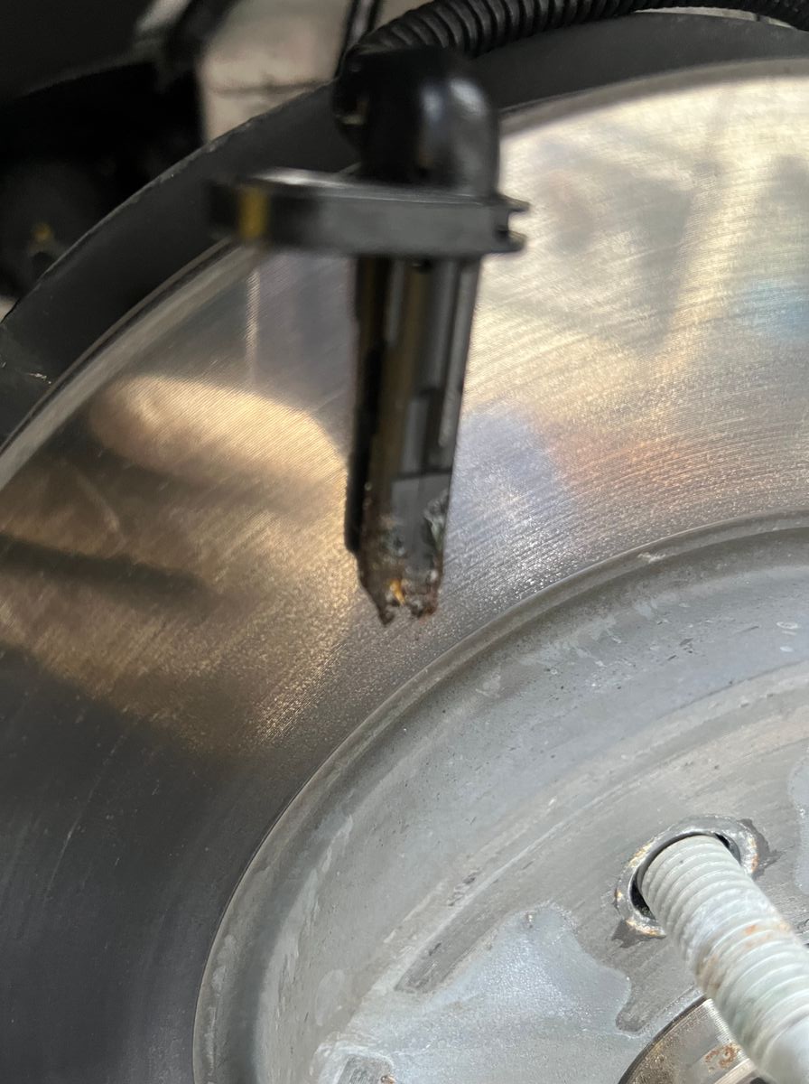 Close-up of the crusty debris packed onto the tip of a Chevrolet Bolt EUV front wheel speed sensor, from a deteriorating anti-click washer